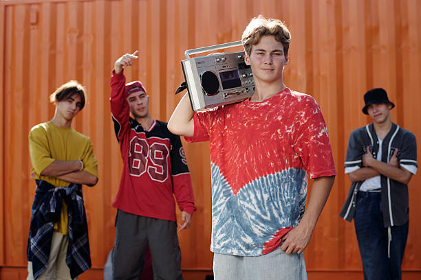 istock Young Men Holding Boombox Against Orange Wall Smiling 2202140741