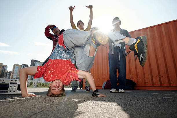 Young man and women performing breakdance on roof during sunset
