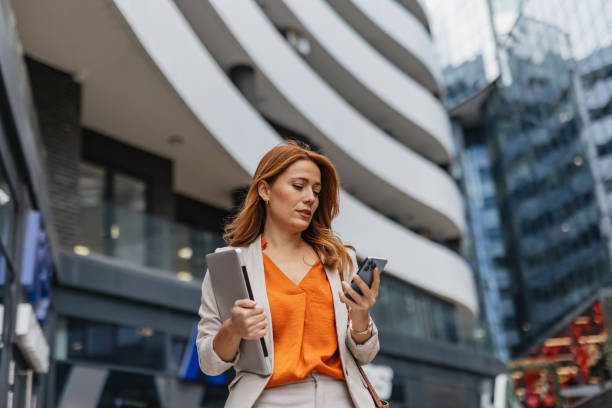 istock Smiling professional woman using phone and laptop outside 2202141777