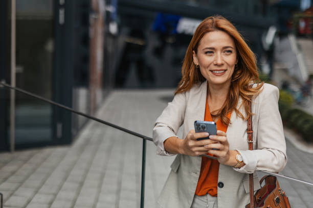 istock Smiling Woman Texting on Phone in City Setting 2202142168