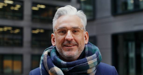istock A gray-haired man smiles looking at the camera while standing in business center 2202142265