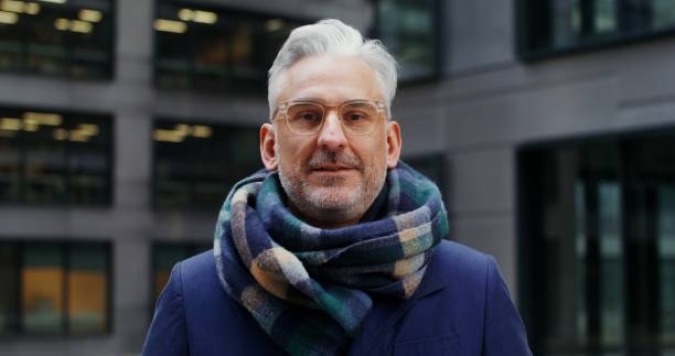 istock A gray-haired man smiles looking at the camera while standing in business center 2202142286