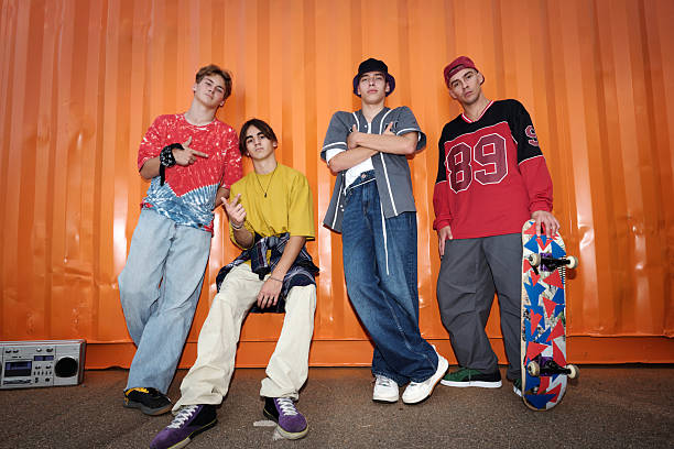 istock Group of Four Young Men Posing Against Orange Background 2202143591
