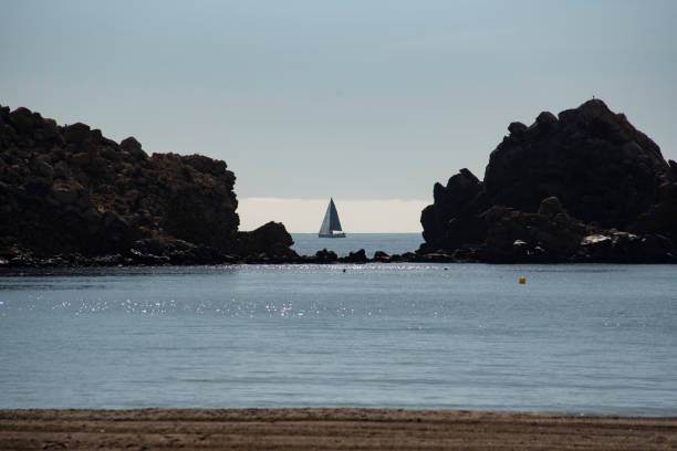 A sailboat between two large rocks in the bay