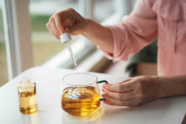 istock Hand holding dropper over tea cup with oil 2202147530