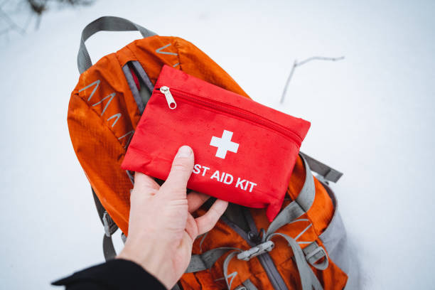 istock In this scene, an individual is prominently holding a first aid kit, which is situated right in front of a bright orange backpack, showcasing important safety and travel essentials 2202147992