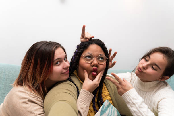 istock Three young women making funny faces on sofa at home 2202148074