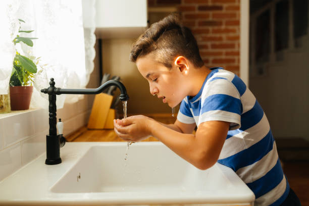 istock Boy Washing His Face with Fresh Water in a Cozy Kitchen 2202152415