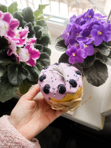 small Easter cake next to a pink violet on the windowsill in hand near the window