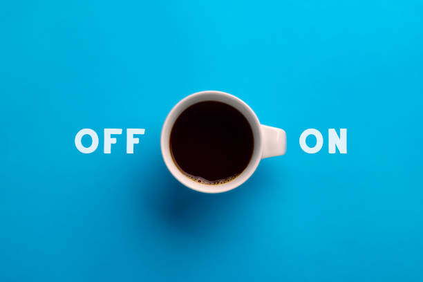 This is an overhead creative image with a white coffee cup on a blue background with the handle being used as the on button to symbolize waking up. The coffee is a rich black color creating a simple graphic image with on and off text. This is a fun creative way to symbolize the power of caffeine in our bodies.