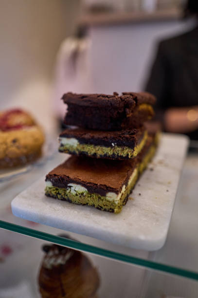 istock Delicious matcha brownie slices stacked on marble tray in bakery display case 2202157389
