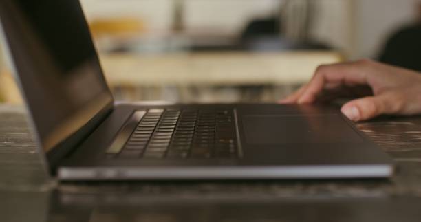 istock A fair-skinned man is typing on a laptop, sitting at a table, close-up 2202159190