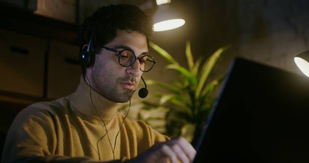 istock Young man talking on the phone using headphones with a microphone and typing 2202159819