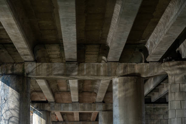 istock Underneath a large highway bridge, concrete pillars and beams create a striking urban landscape illuminated by natural light, showcasing structural design. 2202161159