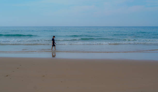 istock lonely person walking on beach at beautiful red sunset 2202161918