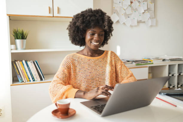 istock Happy female freelancer using laptop at table in home office 2202162208