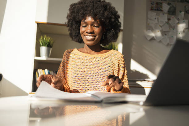 istock Happy young woman reading document while working with laptop at home 2202162986