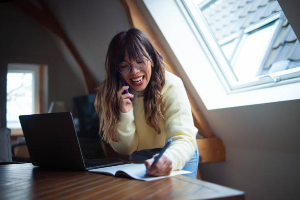 istock Young Professional Woman Writing Notes While on a Phone Call at Home 2202165969