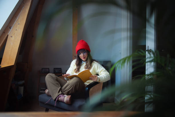 istock Young Woman Relaxing with a Book in a Cozy Rustic Room 2202165997