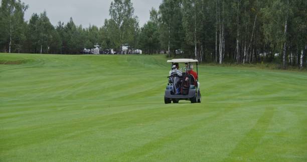 istock Two men are driving a golf car on a golf course and talking to each other 2202166463