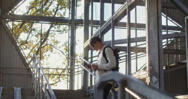istock A man uses a mobile phone and drinks coffee standing on a metal staircase 2202167107