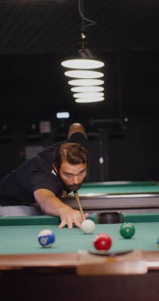 istock A man intently aims and hits billiard ball with a cue, driving it into the hole 2202168140