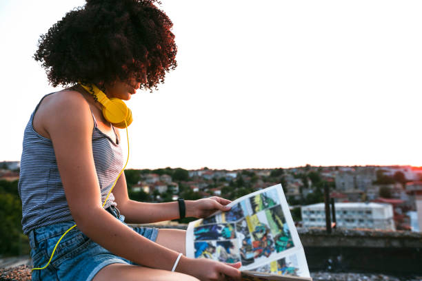 istock Teenage girl reading a comic on a rooftop 2202168144