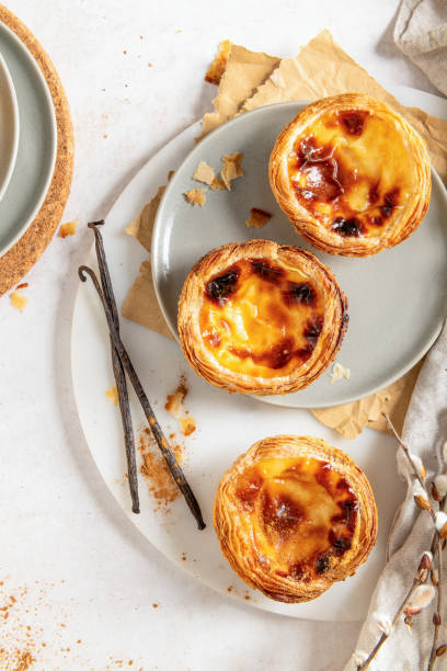 istock Three Pastel de Natas on a plate with vanilla beans and willow branches. Top view 2202171427