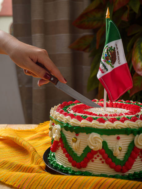 A close-up view of a hand using a knife to cut a Mexican-themed cake.