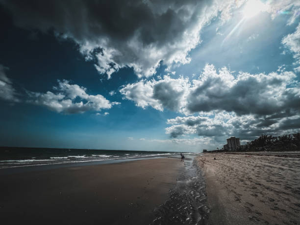 istock Cloudy beach day with distant buildings and shoreline activity near water 2202172068