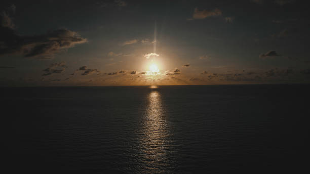 istock Sunset over calm ocean waters with sun's reflection shining on the surface 2202172893