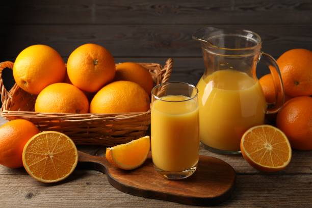 istock Tasty fresh oranges and juice on wooden table 2202175491