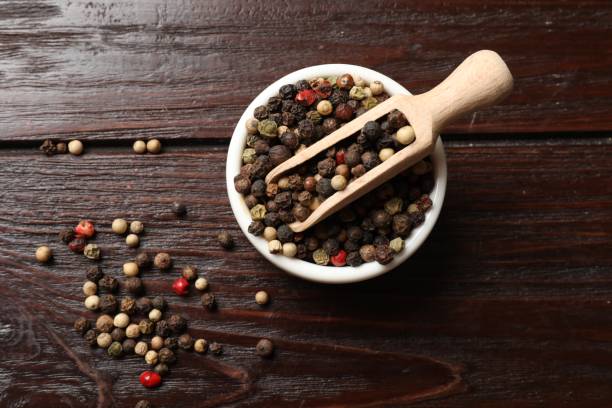 istock Aromatic spice. Different peppers in bowl and scoop on wooden table, top view 2202175585