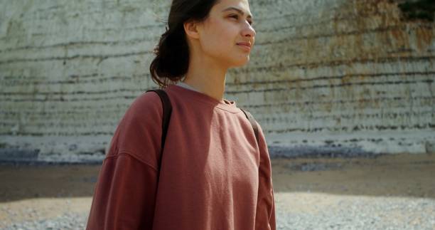 istock A young woman walks along a pebbly beach past sheer chalk cliffs 2202177584