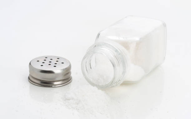 istock Salt shaker tipped over with granules scattered on a white surface in a kitchen setting 2202178495