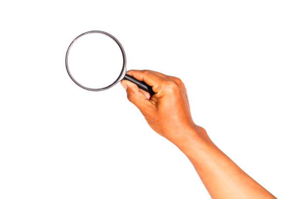 istock Man's hand holding a magnifying glass isolated on white background. 2202184035