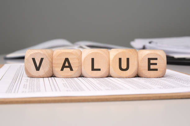 istock wooden cubes spelling 'VALUE' on an office desk with financial documents and paperwork 2202186181