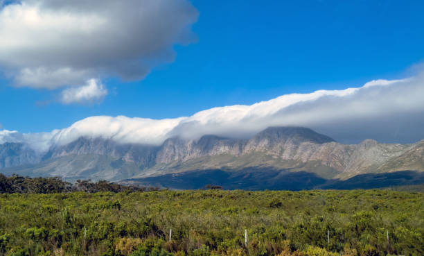 Mountain landscape with a dramatic cloud over the peaks. Tablecloth effect on mountains range. Table Mountain, South Africa Mountain landscape with a dramatic cloud over the peaks. Tablecloth effect on mountains range. Table Mountain, Cape town South Africa table mountain and the tablecloth stock pictures, royalty-free photos & images