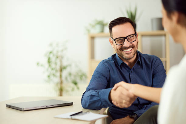 Professional Interaction Featuring a Smiling Man and a Handshake in a Modern Office stock photo