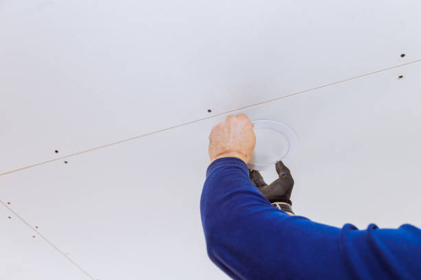istock Worker installing lighting fixture into newly constructed ceiling in modern building 2202188606