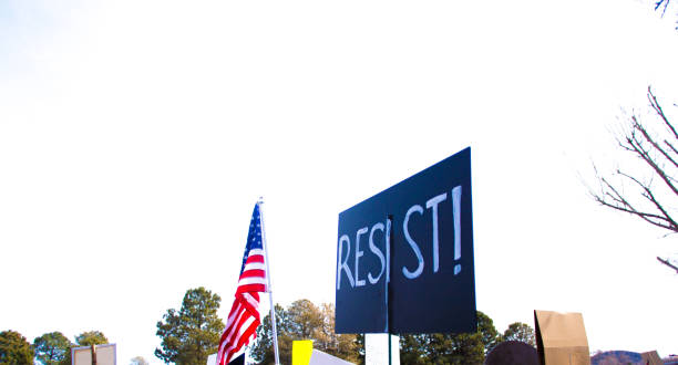 People Holding Protest Sign (RESIST) AND US Flag
