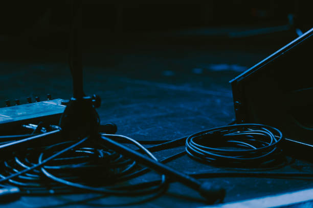 Amps Cords and Mic Stands on a Dark Lit Stage