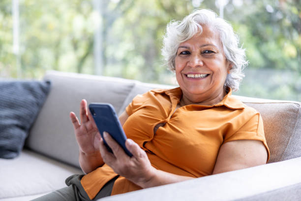 istock Happy senior woman using her phone and looking at the camera smiling 2202195040