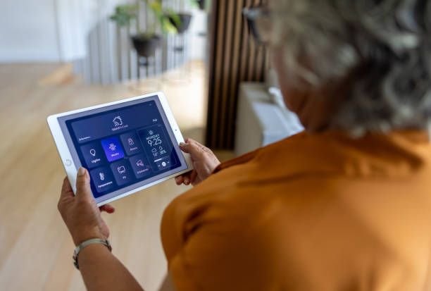 istock Senior woman controlling the music at home using a digital tablet 2202195058
