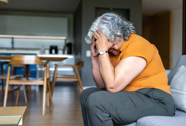 Senior woman at home battling with depression and sitting on the sofa looking distraught