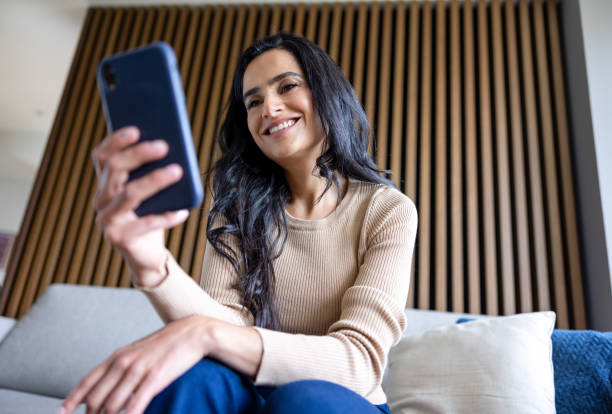 istock Happy woman at home texting on her cell phone and smiling 2202195098