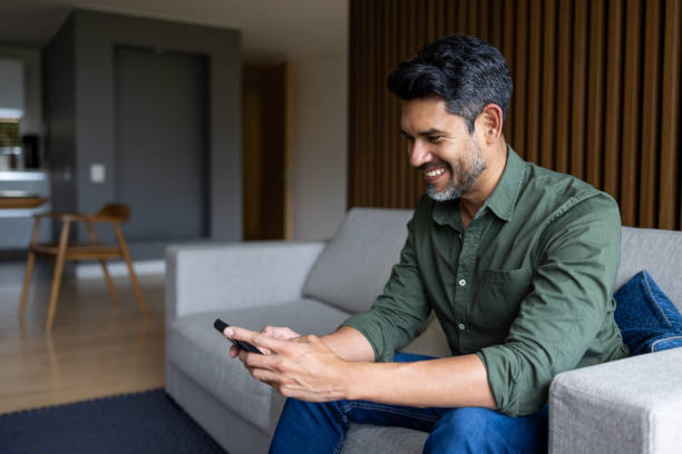 istock Happy man at home texting on his cell phone and smiling 2202195603