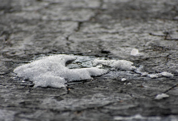 A small circle of snow on cracked blacktop.