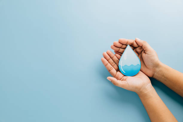 istock World Water Day. Hands hold water drop paper cut on blue background, symbolizing care, saving water 2202200857