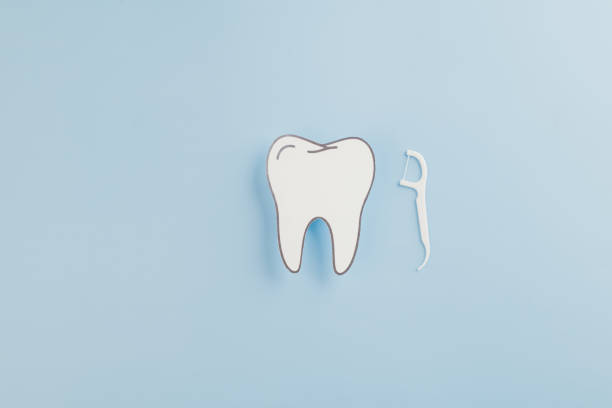 istock Dentist Day concept. A paper tooth model and floss on a blue background 2202200905